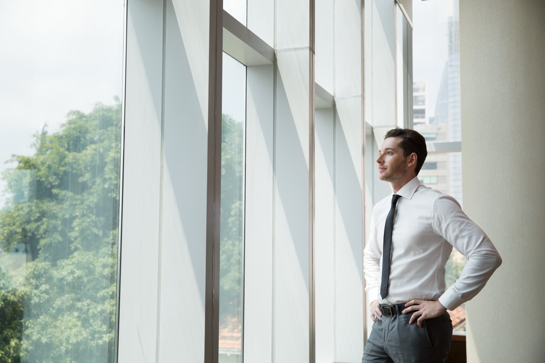 Professional looking out over the city from a bright office