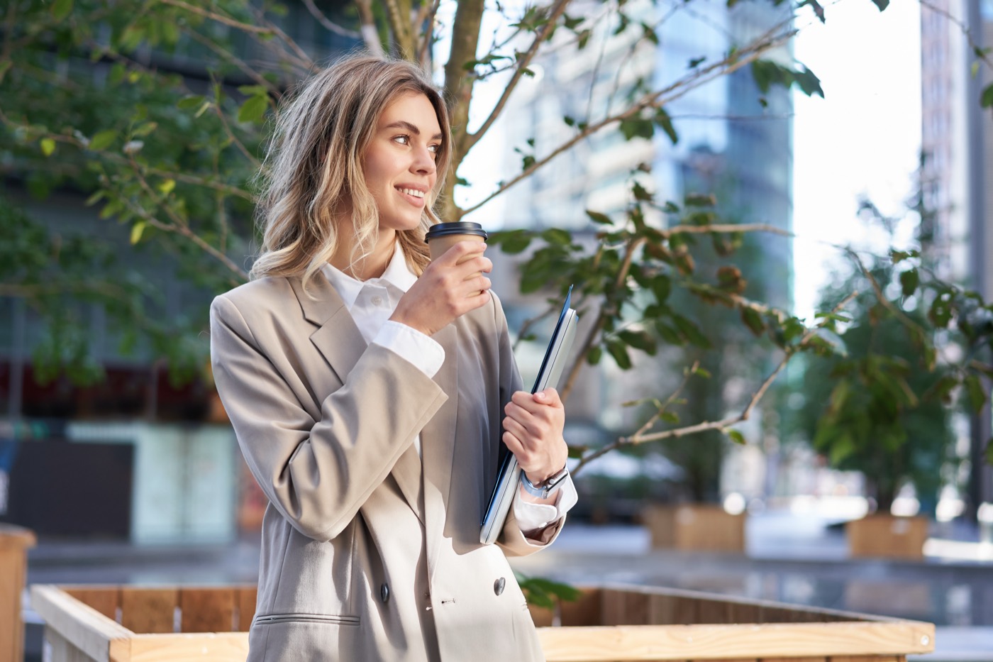 Professional with a coffee and laptop on her way to the office